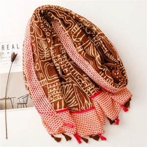 Bohemian ethnic print scarf with tribal patterns and tassels on a minimalist white setup