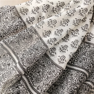Close-up of black floral print on cotton linen scarf with elegant tassel fringe details