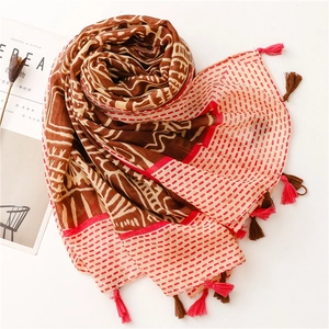 Detail of bohemian scarf with wave patterns, geometric prints and pink fringe tassels