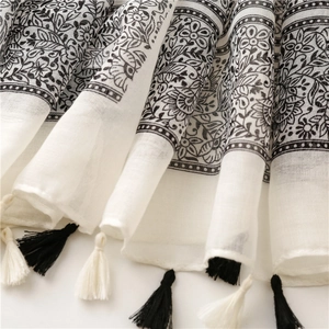 Detail of bohemian floral print and black and white fringe on a white cotton shawl