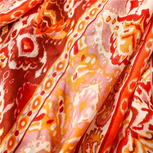 Nahaufnahme von Bohemian-Paisley-Muster und weicher Baumwollstruktur auf orangefarbenem Schal