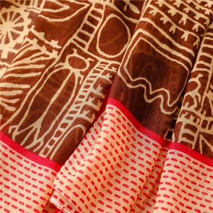 Detail showing the ethnic geometric pattern and vibrant red borders on soft boho scarf