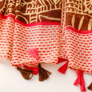 Detail of bohemian shawl featuring ethnic geometric patterns and red fringe tassels