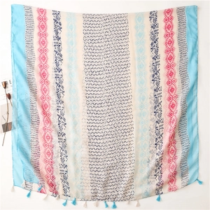 Detailed view of lightweight scarf with floral patterns and blue fringe tassels decoration
