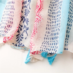 Close-up of lightweight floral scarf with delicate fringe tassels and blue print pattern