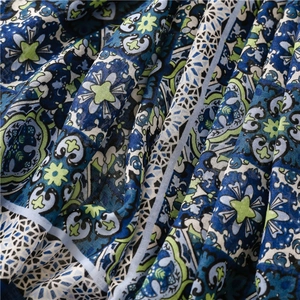 Detailed close-up of bohemian floral print scarf with blue and green tassel fringe