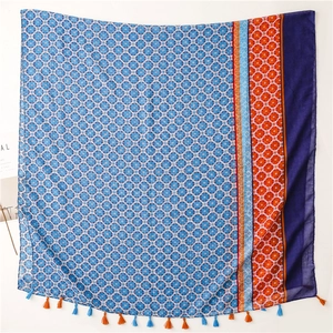 Flat lay of square bohemian shawl with blue geometric prints and tassel edge detail