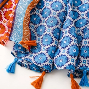 Detail of bohemian scarf with blue sunflower prints and colorful tassel fringes