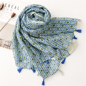 Detail of bohemian floral scarf with delicate blue tassels and lightweight printed fabric