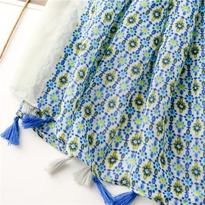 Detail of blue floral bohemian scarf featuring handcrafted dark blue and grey tassels
