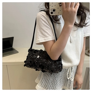 Détail du sac à bandoulière en paillettes noires montrant la texture et la fine lanière