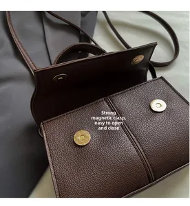Close-up of golden magnetic buckles on dark brown pebble leather crossbody bag