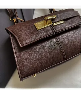 Close-up of dark brown lychee leather handbag featuring a premium gold turn-lock closure