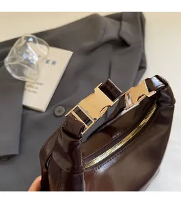 Detailed close-up of dark brown glossy leather handbag with gold metal buckle accents