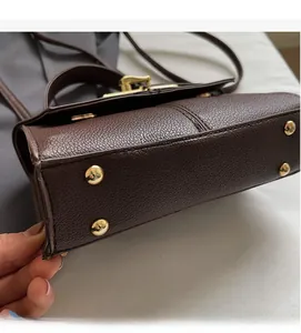Detail of dark brown leather bag base featuring four protective gold metal rivets