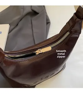 Close-up of smooth gold zipper and premium brown glossy leather with logo embossed