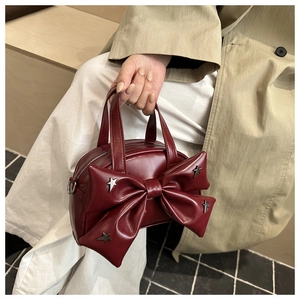 Detail of burgundy handbag with a large bow decoration and silver star studs