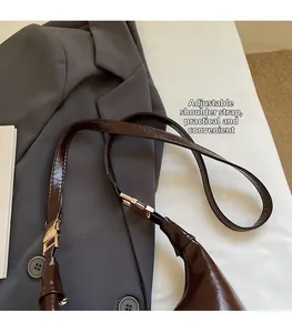 Detail of adjustable shoulder strap with gold metal buckle on dark brown leather bag