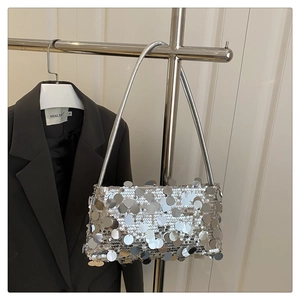 Detail of silver sequin shoulder bag on a hanger with a dark grey suit background