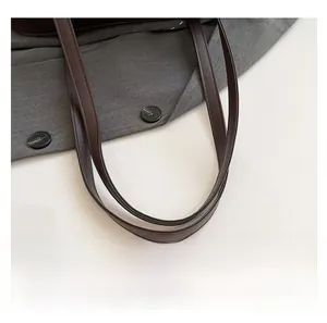 Detail shot of the durable brown leather dual shoulder straps on a minimalist tote bag
