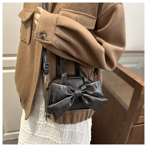 Detalle del bolso bandolera vintage con lazo grande y remaches metálicos de estrella