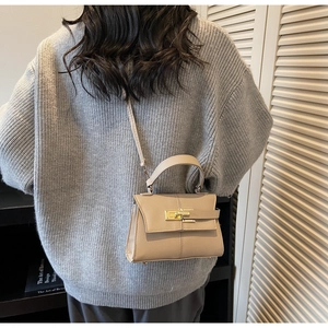 Detail of beige trapezoid handbag with gold rotating lock and fine textured leather