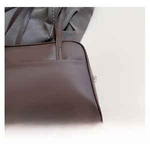 Close-up of matte dark brown PU leather corner and handle stitching on a tote bag