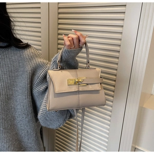 Detail of beige trapezoid bag with lychee grain leather and gold metal twist lock