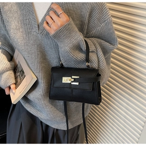 Detail of black pebbled leather trapezoid bag with elegant gold twist lock and strap