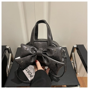 Detailed view of the dark grey leather handbag with large bow and star metal studs