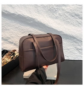 Detailed view of dark brown tote bag featuring matte leather texture and front pocket