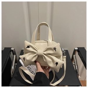 Detail of cream bow handbag with black star studs on a stylish black leather chair