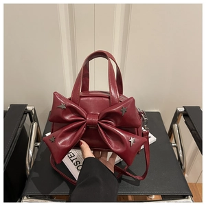 Detail of burgundy bow handbag with silver stars and glossy patent leather finish