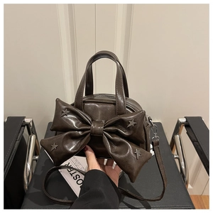 Detail of dark brown bow handbag with silver star rivets and premium leather texture