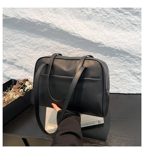 Detail view of large black matte faux leather shoulder bag with sleek front pocket