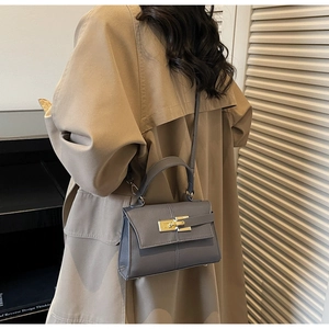 Detail of grey lychee textured trapezoid bag with gold lock and thin shoulder strap
