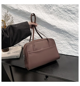 Detail of tan matte leather tote bag with flat front pocket and silver zipper closure