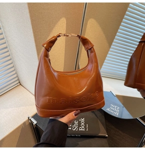 Macro view of brown leather bag with embossed logo and unique twisted handle detail