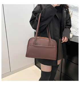 Detail of minimalist dark brown leather tote bag with functional front pocket and shoulder strap