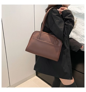 Detail view of brown faux leather tote bag with exterior pocket and slim shoulder straps