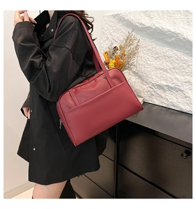 Close-up of a deep burgundy tote bag with front pocket detail and long shoulder straps