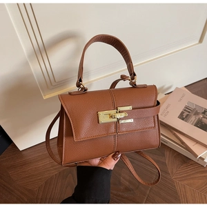 Detail of lychee textured brown leather handbag with vintage golden metal buckle clasp