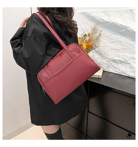 Detail of dark red matte leather tote bag with front pocket shown in a lifestyle setting
