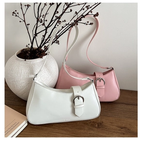 Detail showing two faux leather hobo bags in white and pink colors on wooden desk