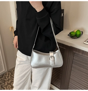 Detailed view of silver metallic crescent bag featuring sleek zipper and decorative buckle