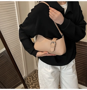 Detail of beige faux leather shoulder bag with large silver metal buckle and slim strap