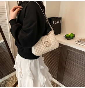 Detail of cream shoulder bag featuring vintage M-pattern and gold circular rotating clasp