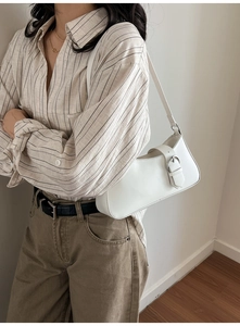 White faux leather shoulder bag shown on model with adjustable strap and D-ring buckle