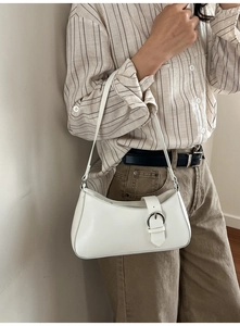 Detail of white baguette shoulder bag featuring a silver buckle and minimalist PU leather texture
