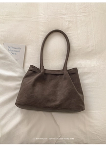 Dettaglio borsa tote in pelle scamosciata marrone scuro con manici sottili e stile retrò